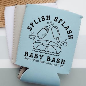 May include: A light blue can cooler with the words "Splish Splash" and "Baby Bash" printed in black. The design includes a baby bottle, popsicle, and inner tube. The text "Baby Ford Arriving July '25" is also printed on the cooler.