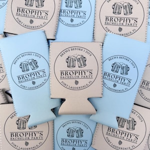 May include: A collection of beer can coolers in light blue and beige. Each cooler features the text "Brophy's Bachelor Party, Fort Lauderdale, FL" in a circular design with beer mugs. The phrase "Brews Before I Do's" is also included.