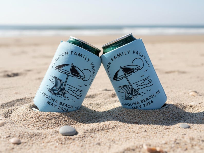 Puede incluir: Dos enfriadores de latas azul claro con dise&ntilde;o de playa, que incluyen una sombrilla, una silla de playa y el texto "JOHNSON FAMILY VACATION CAROLINA BEACH, NC MAY 2026." Est&aacute;n en la arena de una playa.