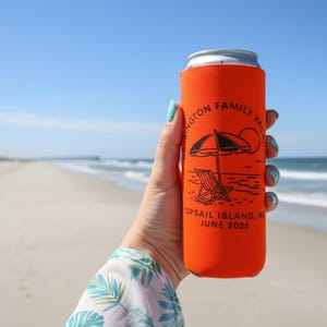 Puede incluir: Un enfriador de latas naranja con texto y gr&aacute;ficos negros, incluyendo una sombrilla y una silla de playa, sobre un fondo de playa. El texto dice "Wellington Family Vacation, Topsail Island, NC, June 2026."