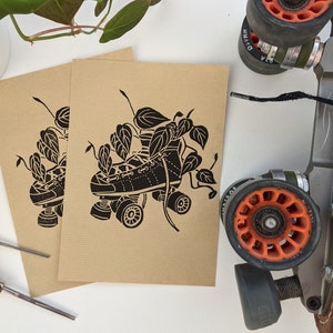 Puede incluir: Ilustración en blanco y negro de un patín con enredaderas de hojas que crecen a su alrededor. El patín está sobre un fondo marrón.