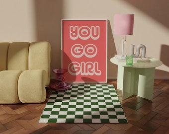 May include: A pink and white poster with the text "You Go Girl" in a retro font, hanging on a wall above a green and white checkered rug. A yellow couch is in the foreground, and a pink lamp with a white base is on a green side table.