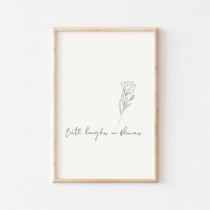 May include: A black and white line drawing of a flower with the text "Earth laughs in flowers" below it. The drawing is framed in a light wood frame.