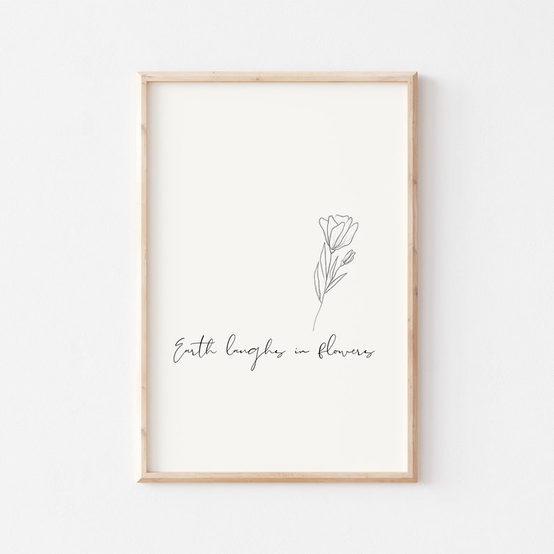 May include: A black and white line drawing of a flower with the text "Earth laughs in flowers" below it. The drawing is framed in a light wood frame.