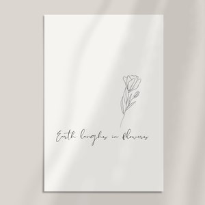 May include: A black and white line drawing of a flower with the text "Earth laughs in flowers" below it.