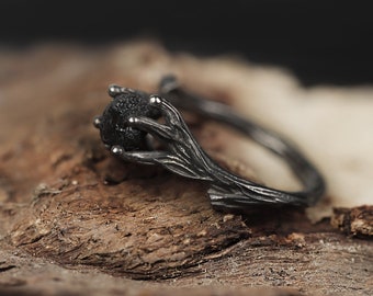 May include: A black ring with a textured, branch-like design. The ring features a black gemstone in the center.