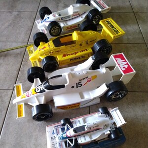K&ouml;nnte beinhalten: Eine Sammlung von f&uuml;nf Spielzeug-Rennwagen, darunter ein wei&szlig;es Auto mit den Aufdrucken "MAC TOOLS" und "BUICK 15", ein gelbes Auto mit den Aufdrucken "Snap-on" und "PENNZOIL" und ein wei&szlig;es Auto mit dem Aufdruck "True Value 2". Die Autos sind alle im Ma&szlig;stab 1:2 und aus Metallguss gefertigt.