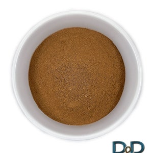 May include: A white bowl filled with a brown powder, likely ground cinnamon.