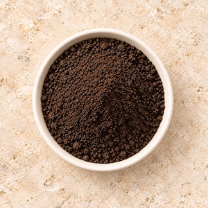 Peut inclure: Un bol rond en céramique blanche rempli d'un tas de marc de café brun foncé et granuleux. La texture du marc est grossière et irrégulière, formant un pic au centre du bol. Le bol présente un bord lisse et propre ainsi qu'un design simple.