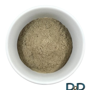 May include: A white bowl filled with a light brown powder. The powder is finely ground and has a uniform texture.