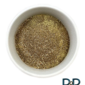 Puede incluir: Un bol de cerámica blanco lleno de un polvo finamente molido de color marrón claro. El polvo está hecho de hierbas secas y tiene una textura ligeramente granulada.