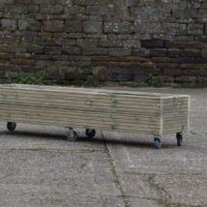 May include: A long, rectangular wooden planter box on wheels. The planter is made of natural wood and has a rustic look. It is perfect for growing herbs, flowers, or vegetables.
