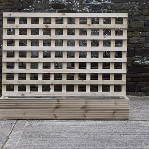 May include: A wooden planter with a lattice panel on the back. The planter is made of natural wood and has a rectangular shape. The lattice panel is made of thin wooden slats that are arranged in a grid pattern.