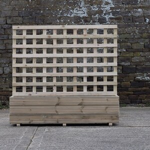 May include: A wooden planter with a lattice trellis on top. The planter is made of natural wood and has a rectangular shape. The trellis is made of thin wooden slats that are spaced evenly apart.