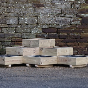 May include: A set of five square wooden planters stacked in a pyramid shape. The planters are made from natural wood and have a rustic look.