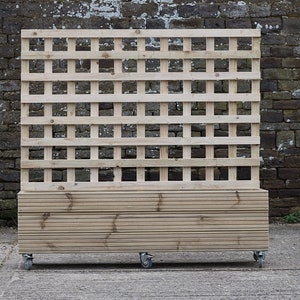 May include: A wooden planter box with a trellis on top. The planter is on wheels and has a natural wood finish.