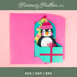 May include: A pink envelope with a pop-up card inside. The card features a penguin wearing a pink and white hat, holding a turquoise gift box with a red ribbon. The text "Furrow & Feather SVG" is at the top of the image.