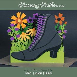 Puede incluir: Un diseño recortado en papel que presenta una bota negra de estilo victoriano con cordones morados, sobre un fondo de flores de papel naranja, amarillo y morado y hierba verde. Se ven las palabras "Furrow & Feather SVG" y "digital cutting file".