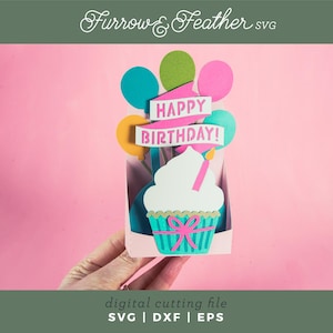 May include: A digital cutting file for a birthday card featuring a cupcake with colorful balloons and the text "Happy Birthday!"