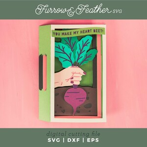 May include: A green and brown card with a pop-up beet. The beet is being held by a hand. The card says "You make my heart beet!"