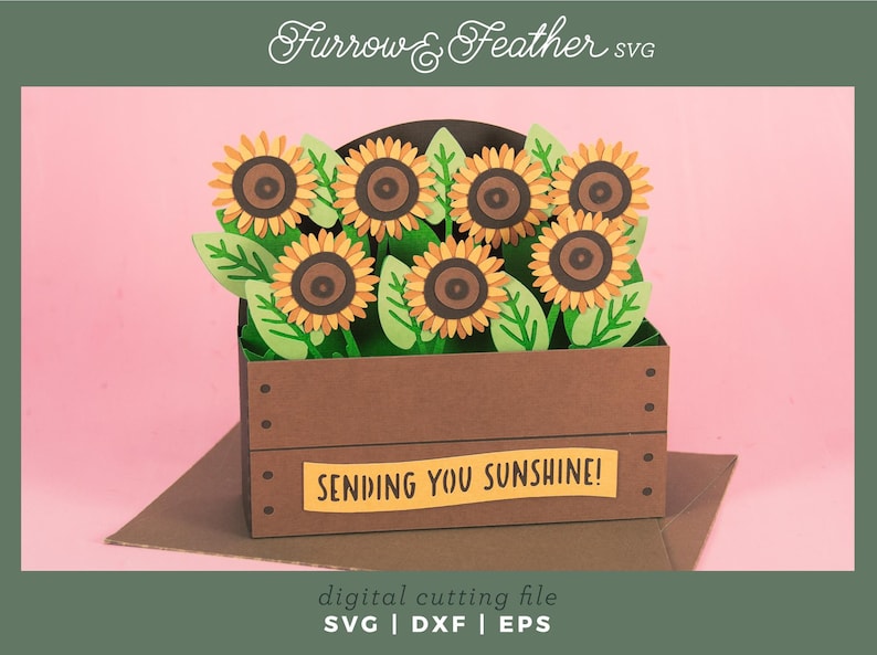 May include: A papercraft of sunflowers in a brown wooden crate, with green leaves and yellow petals. The crate has a yellow banner that reads "SENDING YOU SUNSHINE!". The image is a digital cutting file.