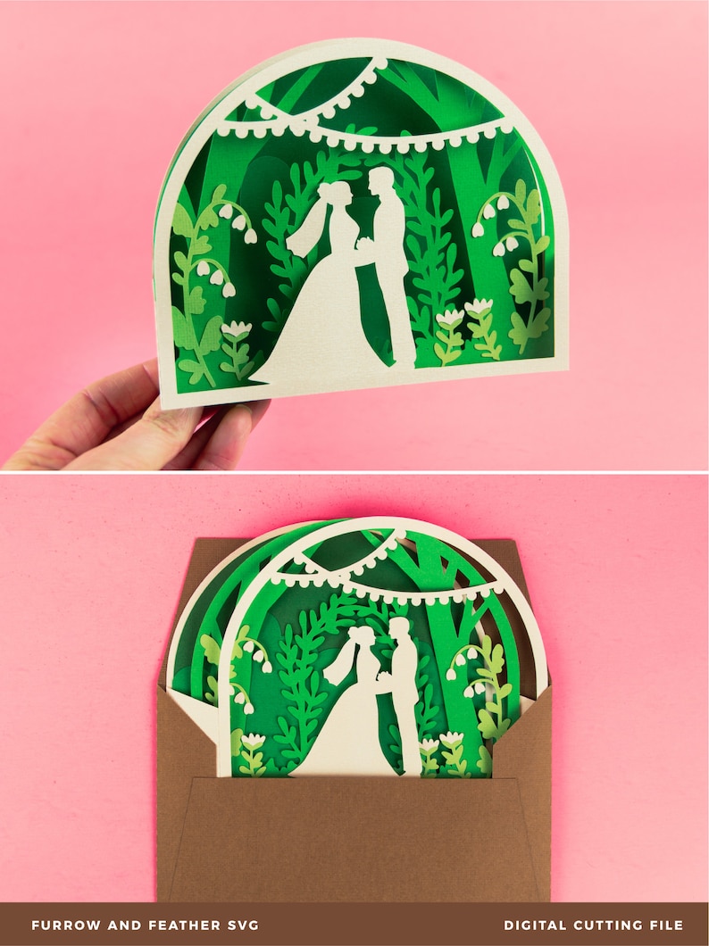 May include: A green and white layered paper cut design of a wedding couple standing under a canopy of trees with string lights. The design is in a brown envelope.