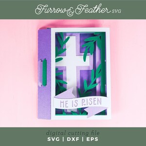 May include: A purple and white layered card with a cross and green leaves. The card has a banner that reads "He is Risen".