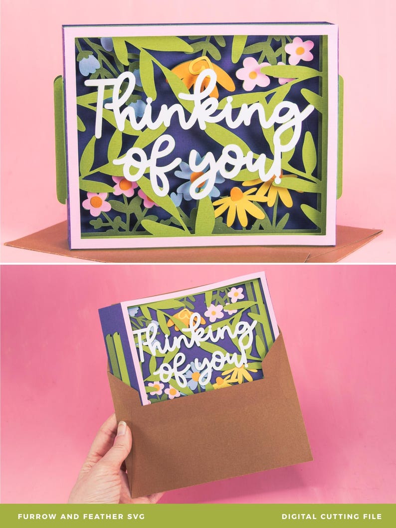 May include: A paper art card with the words "Thinking of you" in white script. The card has a floral design with green leaves, yellow and pink flowers, and a purple background. The card is in a brown envelope.
