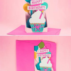 May include: A pink card with a pop-up cupcake and balloons. The card reads "Happy Birthday!" in pink letters.