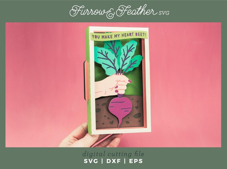 May include: A digital cutting file for a card with a beet and the text "YOU MAKE MY HEART BEET!" The beet is green and purple and is being held by a hand. The card is in a frame with a green and white border.