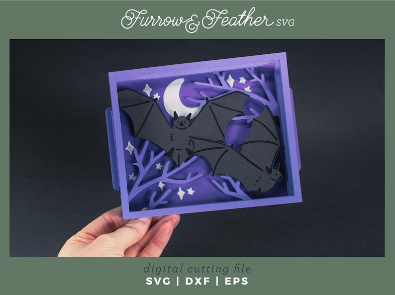 Pode incluir: Uma pe&ccedil;a de arte em papel em camadas com dois morcegos pretos em silhueta contra um fundo roxo com uma lua crescente e estrelas. A obra de arte est&aacute; em uma moldura roxa com o texto "Furrow & Feather SVG" e "digital cutting file SVG | DXF | EPS".