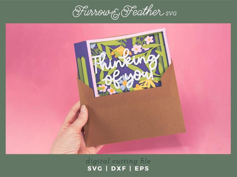 May include: A papercraft card with the words "Thinking of you" in white script, surrounded by colourful paper flowers and foliage. The card is inside a brown envelope, set against a pink background. The image also includes the text "digital cutting file SVG | DXF | EPS".