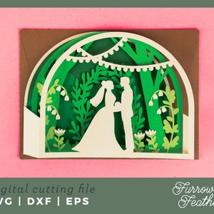 May include: A white silhouette of a couple standing in a green forest with white flowers and string lights. The image is a digital cutting file for a wedding card.