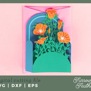 May include: A digital cutting file featuring a pop-up card design with a bouquet of orange California poppies in a blue and green archway. The file is available in SVG, DXF, and EPS formats. Furrow & Feather.