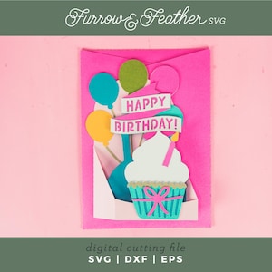 May include: A pink card with a pop-up cupcake design. The cupcake is decorated with a white frosting, a pink bow, and a blue and white striped cupcake liner. The card also features a banner that says "Happy Birthday!" and colorful balloons.