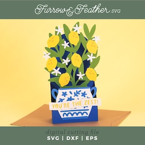 May include: A three-dimensional paper craft card featuring a blue and white vase filled with green lemon tree branches, yellow lemons, and white flowers. A white banner across the front of the vase displays the yellow text YOU'RE THE ZEST!