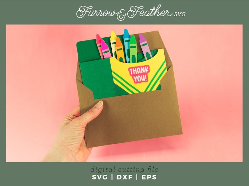 May include: A brown envelope with a green card inside. The card has a yellow and green design with the words "Thank You!" in pink letters. There are six colorful crayons sticking out of the top of the card.