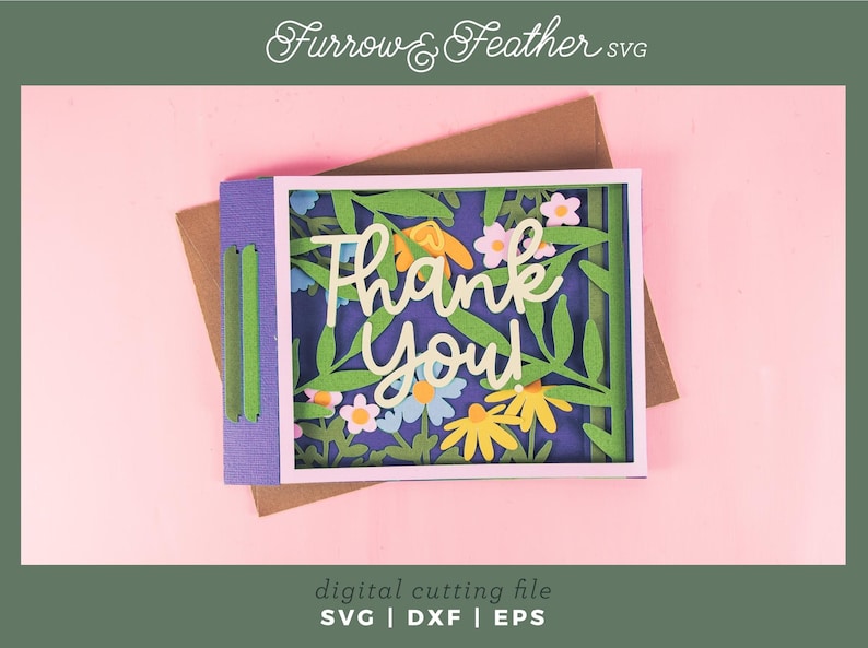 May include: A layered paper card with a floral design and the words "Thank You" in white script. The card features green leaves, yellow and white flowers, and a purple border. The background is a light pink color.