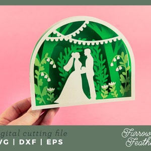 May include: A digital cutting file design featuring a wedding couple standing under a leafy archway with a string of lights. The design is in a green and white color scheme and includes floral details.