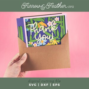 May include: A brown envelope holds a floral "Thank You" card with a blue background. The card features white script and colorful flowers. The image has a pink background and the text "Furrow & Feather SVG" at the top.