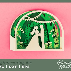 May include: A white paper cut-out design of a wedding couple standing under a green leafy archway with white flowers and string lights. The design is on a pink background. The text "Furrow & Feather" is in the bottom right corner.