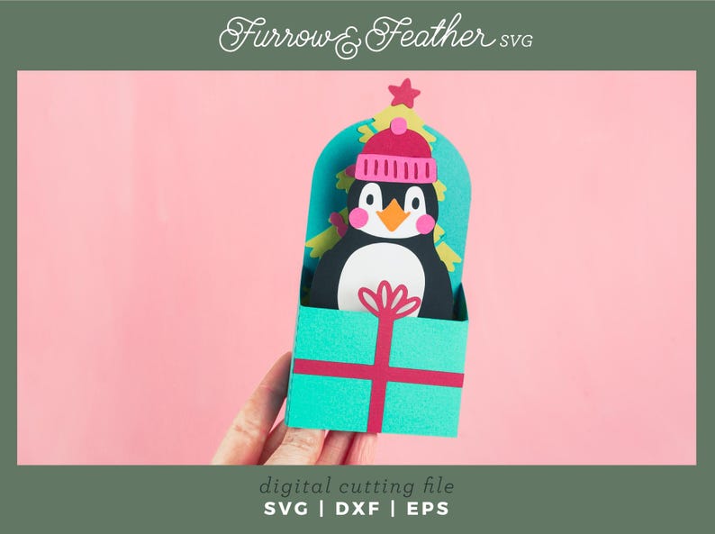 May include: A teal blue gift box with a red ribbon and a penguin wearing a pink hat peeking out of the top. The penguin is surrounded by a green Christmas tree.