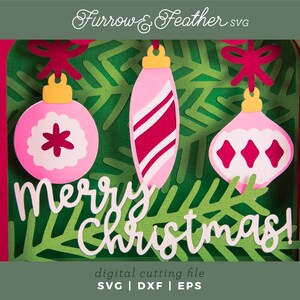 May include: A layered Christmas-themed digital cutting file featuring three pink ornaments with white accents and a green fir tree background. The words "Merry Christmas!" are in white script. The design includes the text "Furrow & Feather SVG" and "digital cutting file SVG | DXF | EPS".