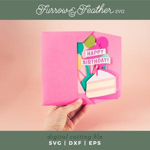 May include: A pink card with a pop-up design featuring a cake, balloons, and a banner that reads "Happy Birthday!"