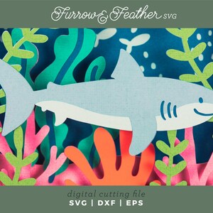 Puede incluir: Un tibur&oacute;n azul claro nada entre coloridos corales y algas marinas en este dise&ntilde;o de archivo de corte digital. La imagen incluye el texto "Furrow & Feather SVG" y "digital cutting file SVG | DXF | EPS". El dise&ntilde;o es adecuado para proyectos de manualidades.