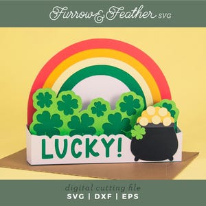 Könnte beinhalten: Ein St. Patrick's Day-Design aus Papier mit einem Regenbogen, grünen Kleeblättern und einem Goldtopf. Das Wort "LUCKY!" wird angezeigt. Es ist eine digitale Schneidedatei, ideal für Bastelprojekte.