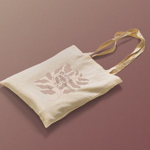 K&ouml;nnte beinhalten: Eine beige Tragetasche mit einem braunen Blumenmuster und dem Text "VERITAS NATURE SHOP COME & SEE" auf der Vorderseite.