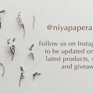May include: White flowers with green stems arranged on a white background. The text '@niyapaperart' is displayed below the flowers. The text 'Follow us on Instagram to be updated on our latest products, sales and giveaways!' is displayed below the '@niyapaperart' text.