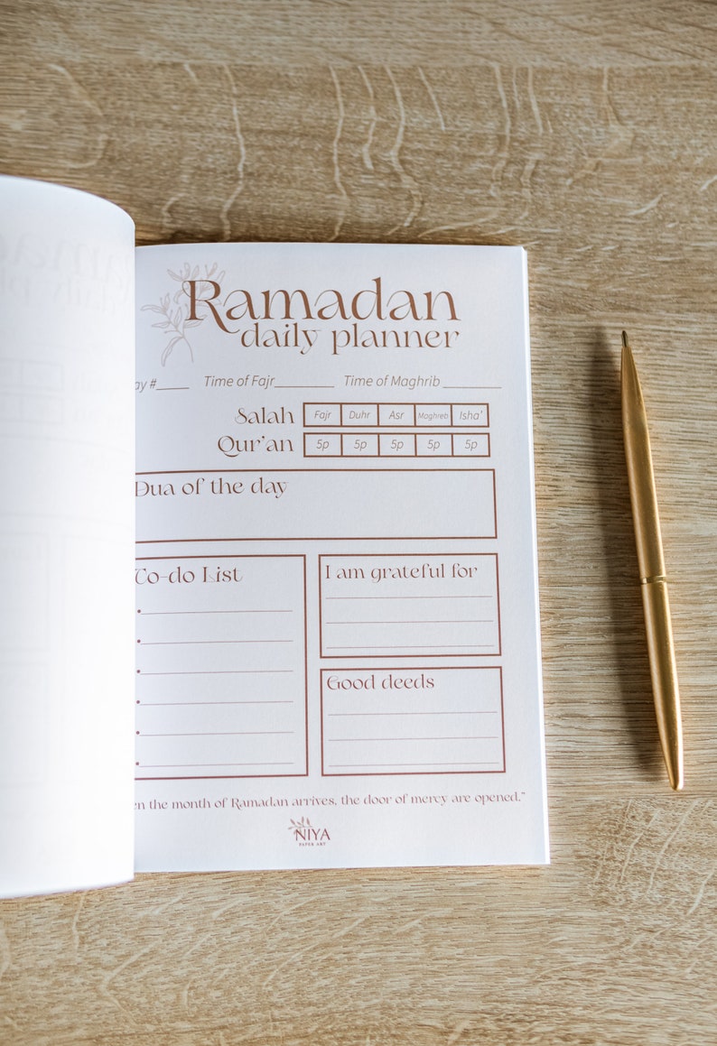 May include: A white daily planner with a brown title "Ramadan daily planner". The planner has sections for prayer times, a to-do list, and gratitude journaling. The text "in the month of Ramadan arrives, the door of mercy are opened." is printed at the bottom.