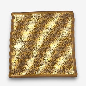 Puede incluir: Un pañuelo cuadrado con un estampado de leopardo en tonos marrón y negro. El pañuelo tiene un borde marrón sólido con una fina línea dorada que acentúa el borde interior. La tela muestra una textura ondulada en toda su superficie.